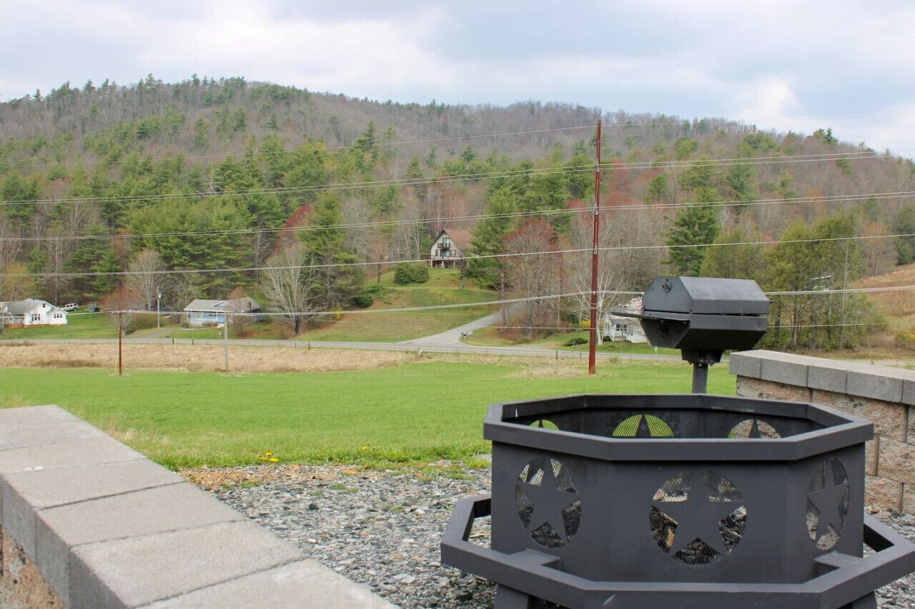 A grassy area with a metal grill and a house in the background.