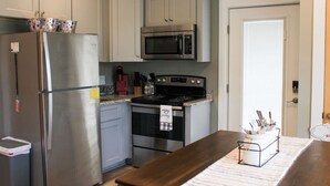 A kitchen with white cabinets, a stainless steel refrigerator, a microwave, and an oven. - Tiny 2br Cabin w/ View | Grill | Fire Pit #3 (West Jefferson)