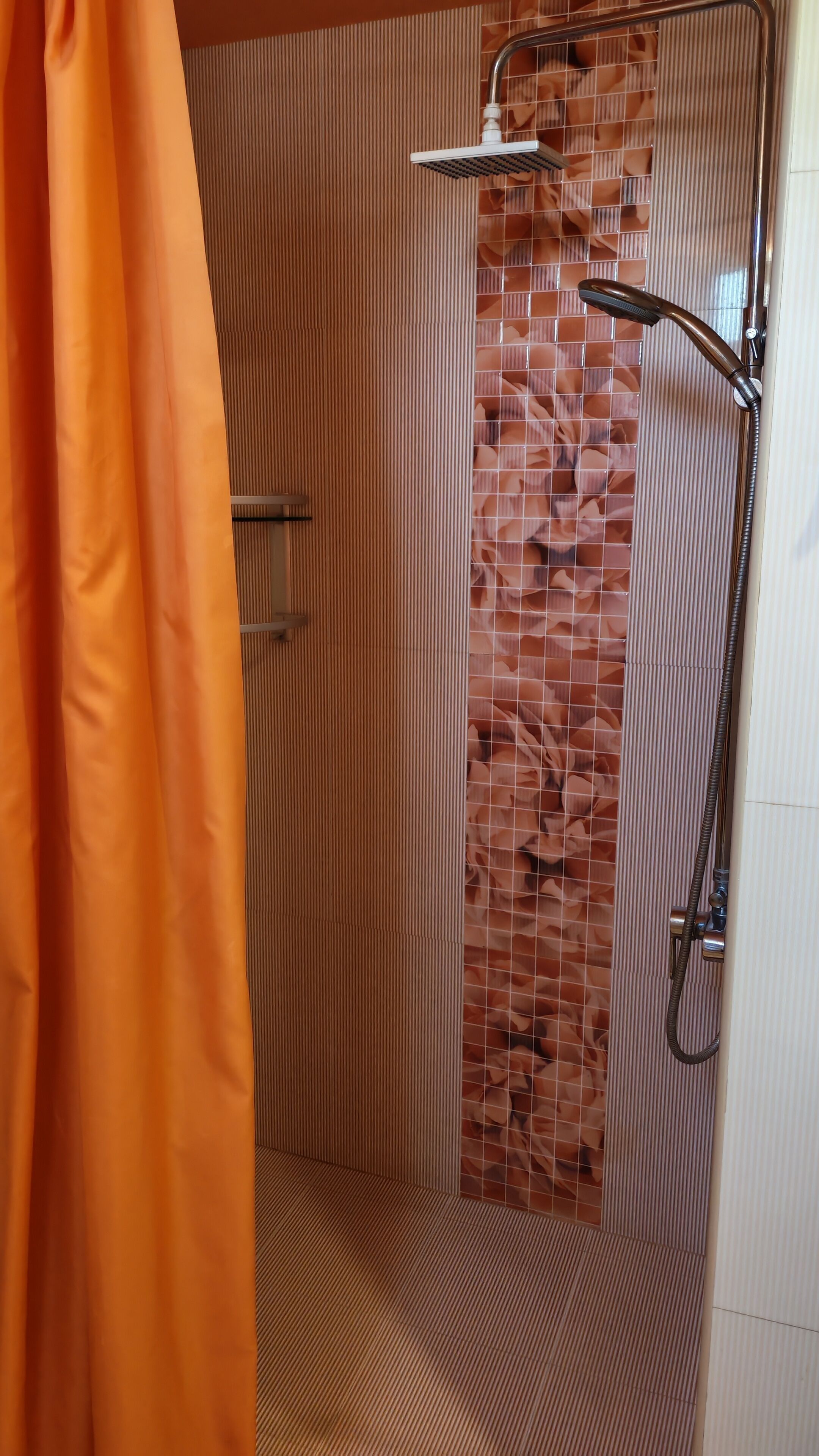 A shower area with a tiled wall, a showerhead, and a curtain.