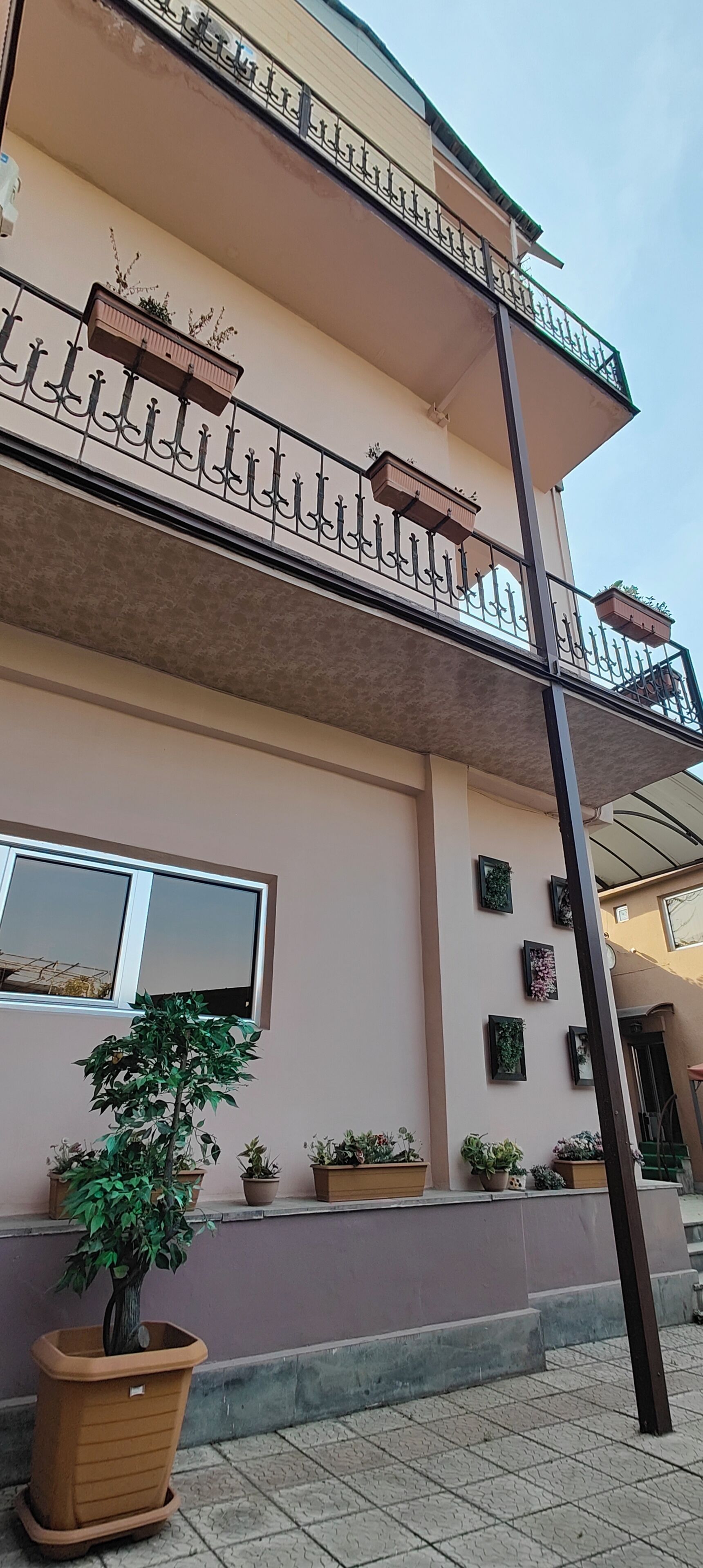 A multi-story building with balconies, potted plants, and a staircase.