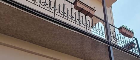 A multi-story building with balconies, potted plants, and a staircase.