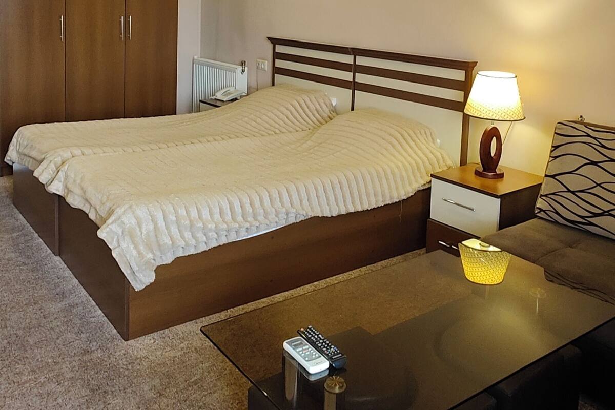 A bedroom with a bed, bedside table, lamp, and a coffee table.