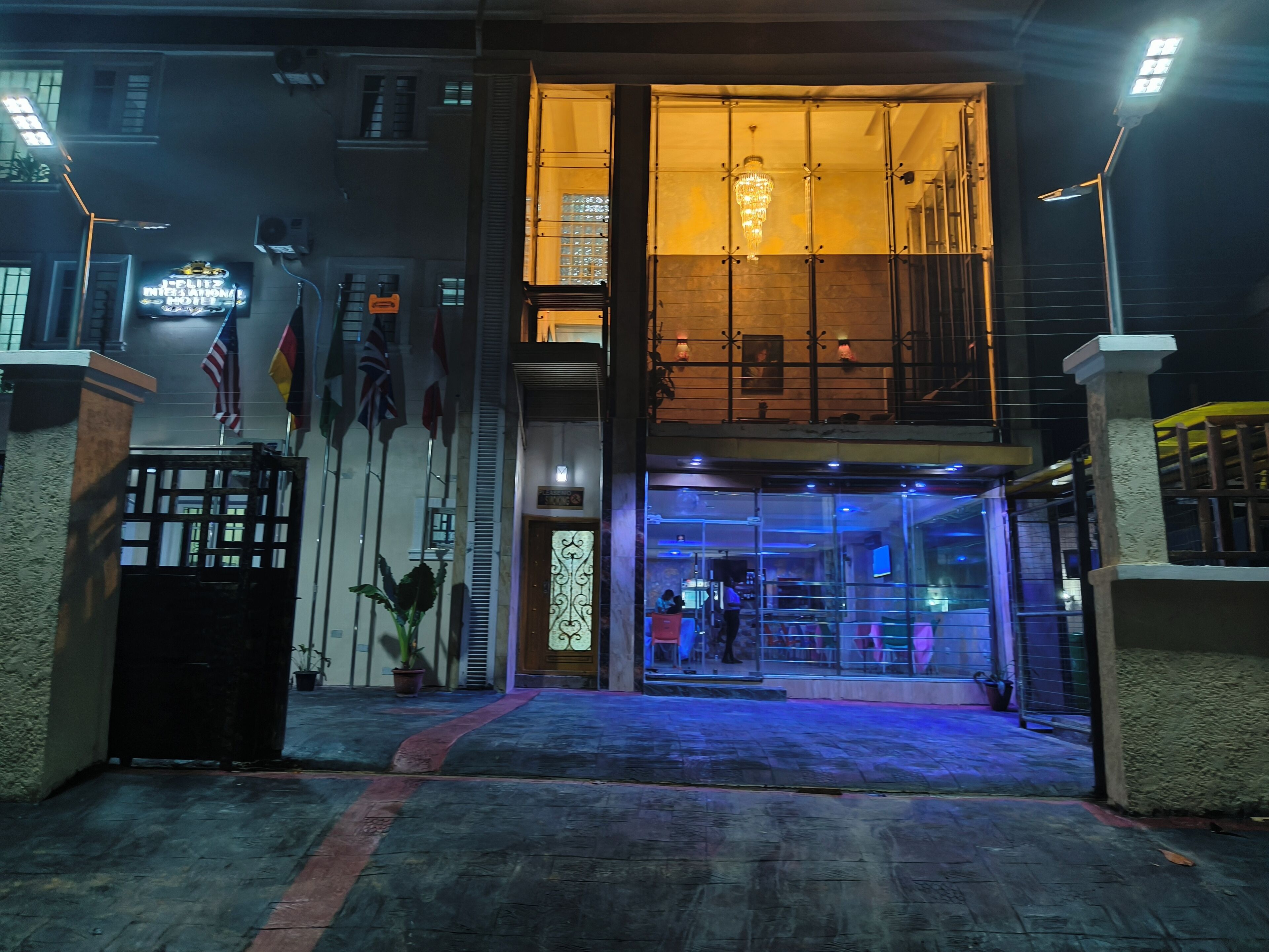 A hotel entrance with a glass facade, a chandelier, and flags.