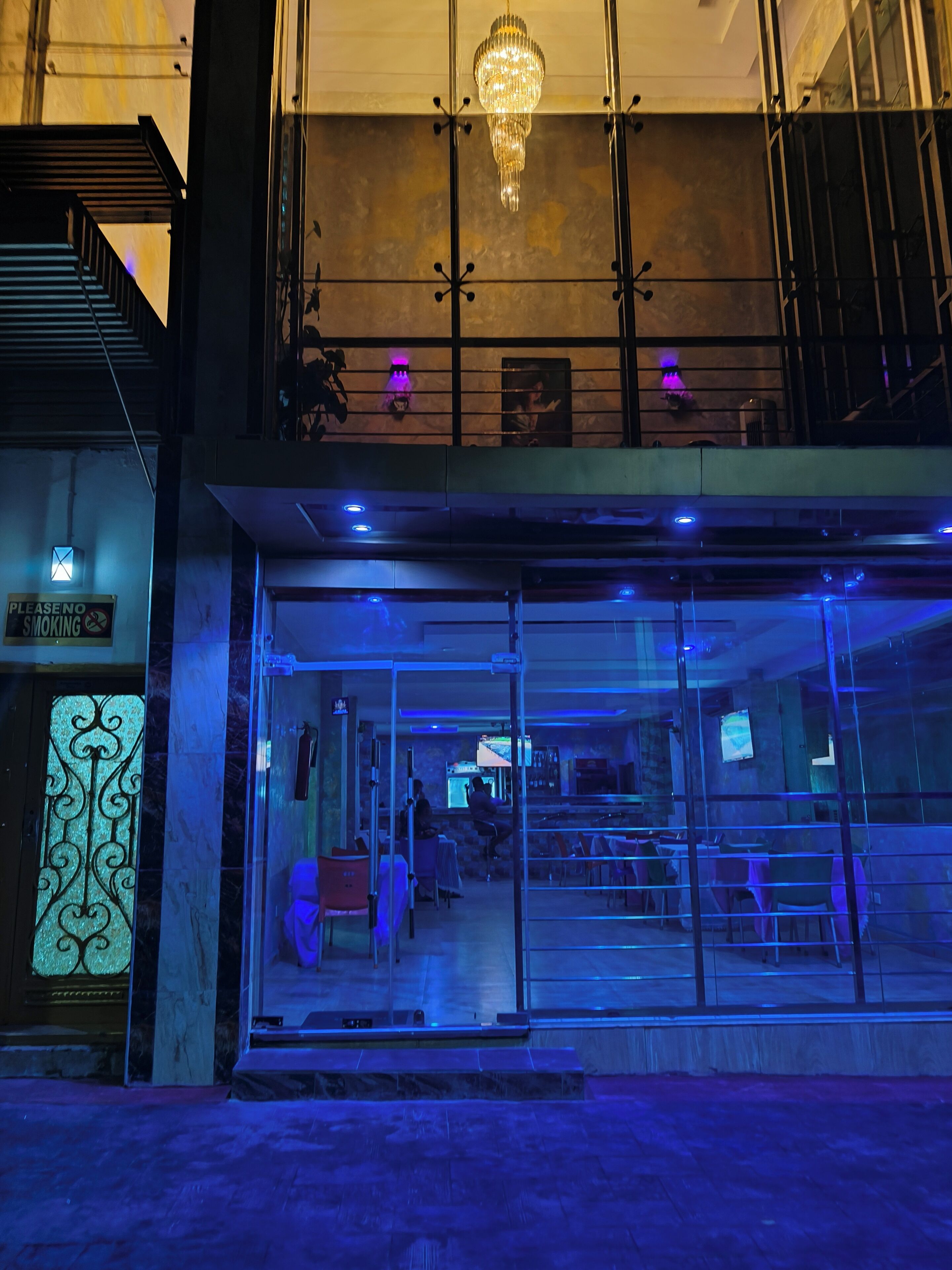 A building with a glass entrance, a chandelier, and a sign indicating no smoking.