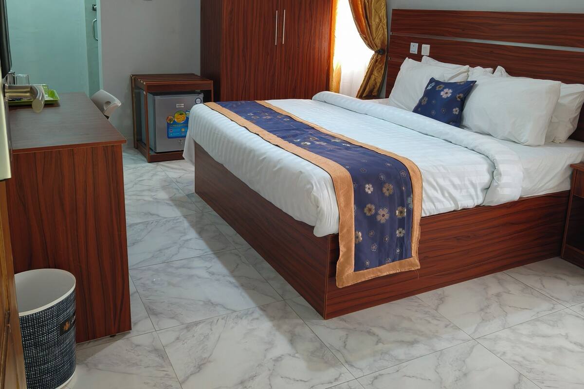 A hotel room with a wooden bed, a desk, a wardrobe, and a bathroom.