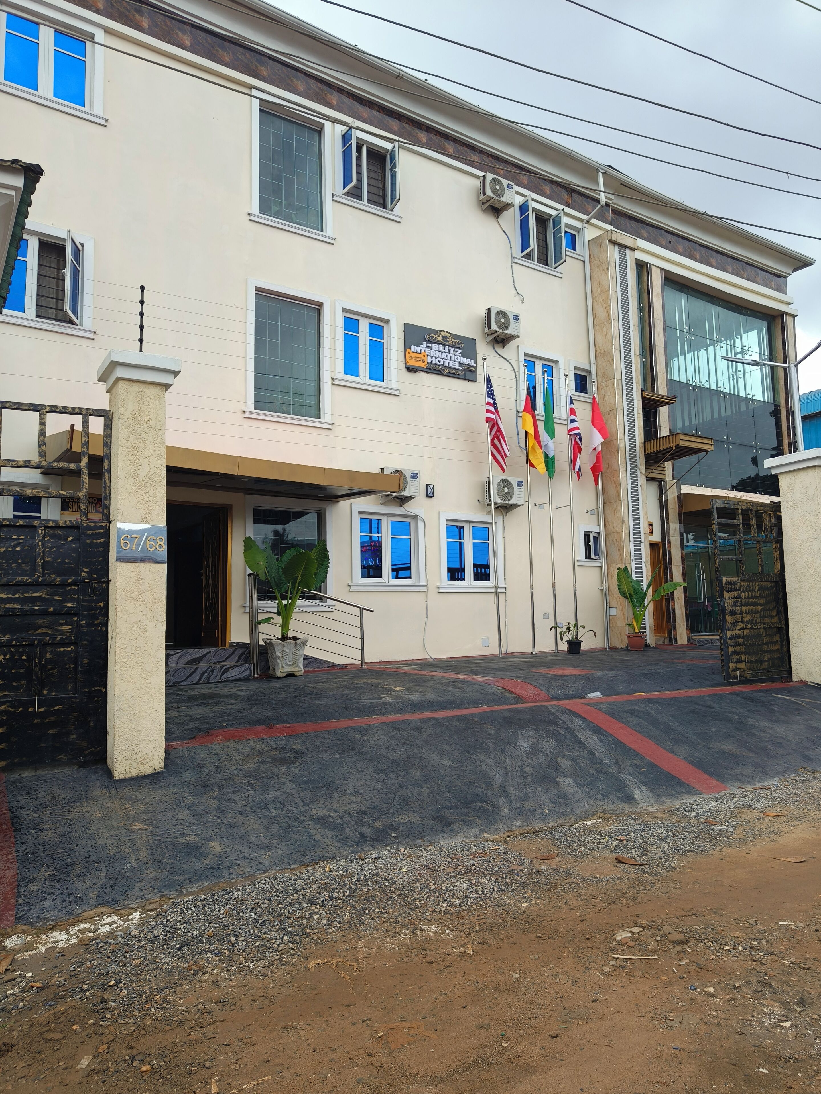Un hôtel à la façade beige, doté de nombreuses fenêtres et d’une enseigne indiquant « Blitz International Hotel ».