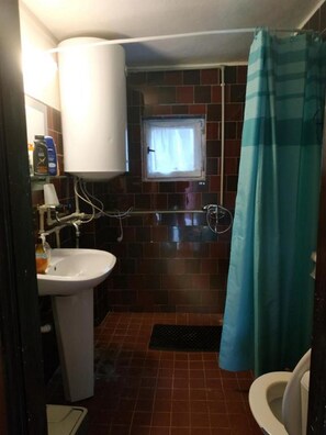 A small bathroom with a white sink, a window, a shower curtain, and a toilet. - LUCKY Kitten (Nova Lesna)