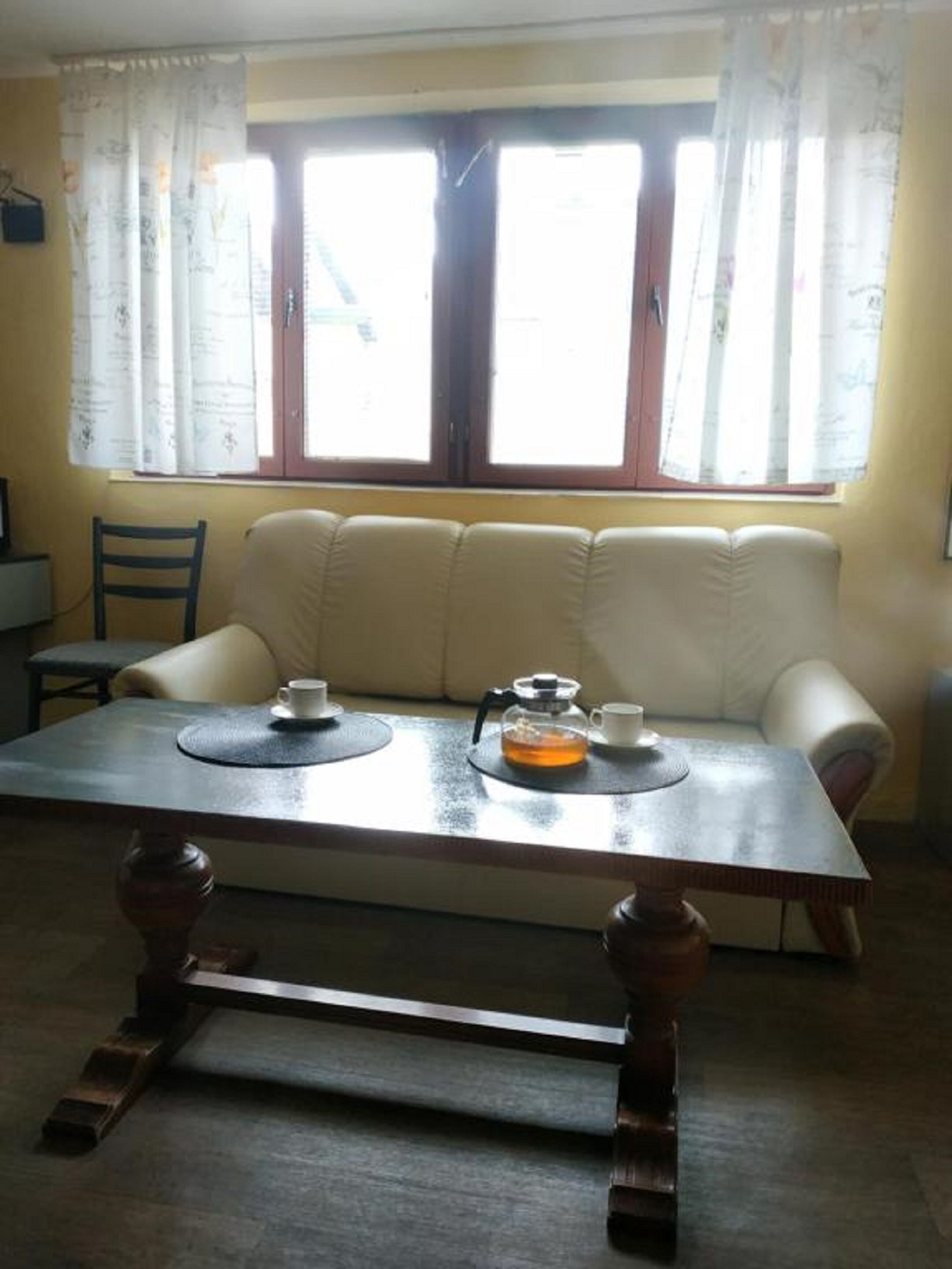 A living room with a sofa, a coffee table, and a window with curtains.