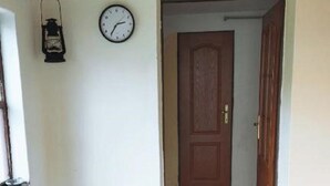 Techo de madera, un reloj, una puerta, un banco y un tapete a rayas.