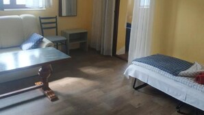 Una habitación con una cama, una silla, una mesita y un espejo en la pared.