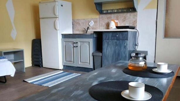 Cocina moderna con una isla central, armarios grises y pared amarilla.