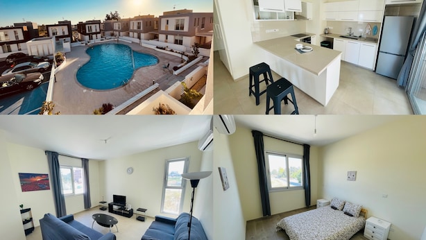 Un apartamento moderno con piscina, cocina con armarios blancos, sala de estar con sofá y televisión, y dormitorio con cama y ventana.
