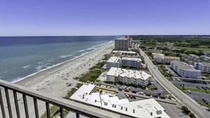 Un paysage urbain côtier avec une plage, des immeubles de grande hauteur et un ciel dégagé.