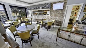 Un restaurant avec des tables et des chaises rondes, un mur en briques et un tableau affichant le menu.