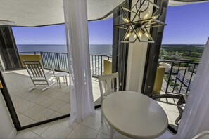 A balcony with a table and chairs, a clock, and a view of the ocean. - New,Top Floor Views,Private Maisons Sur Mer,Pools! (Myrtle Beach)