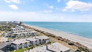 Una zona residencial costera con edificios de varios pisos, una playa y cielo despejado.