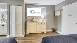 A bedroom with a bed, a dresser, a mirror, and a television displaying 'BIG FISH RENTALS'.