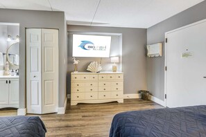 Une chambre à coucher comprenant un lit, une commode, un miroir et un téléviseur affichant le logo « BIG FISH RENTALS ».