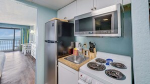 Une cuisine compacte équipée d’un réfrigérateur, d’un four à micro-ondes, d’un évier et d’une cuisinière.