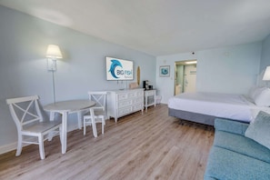 Una camera d'albergo con un letto, una scrivania con una sedia, un comò e una lampada a parete.
