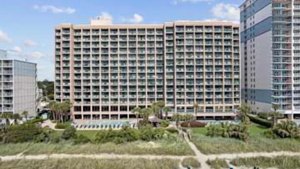 Un hôtel de grande hauteur, avec de nombreux étages, une cour intérieure et des espaces verts environnants.