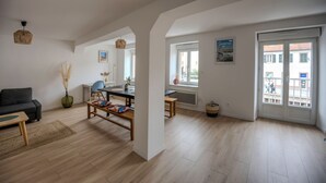 Un vaste espace de vie comprenant un canapé, une table à manger et des chaises. Une grande fenêtre offre une vue sur l’extérieur.