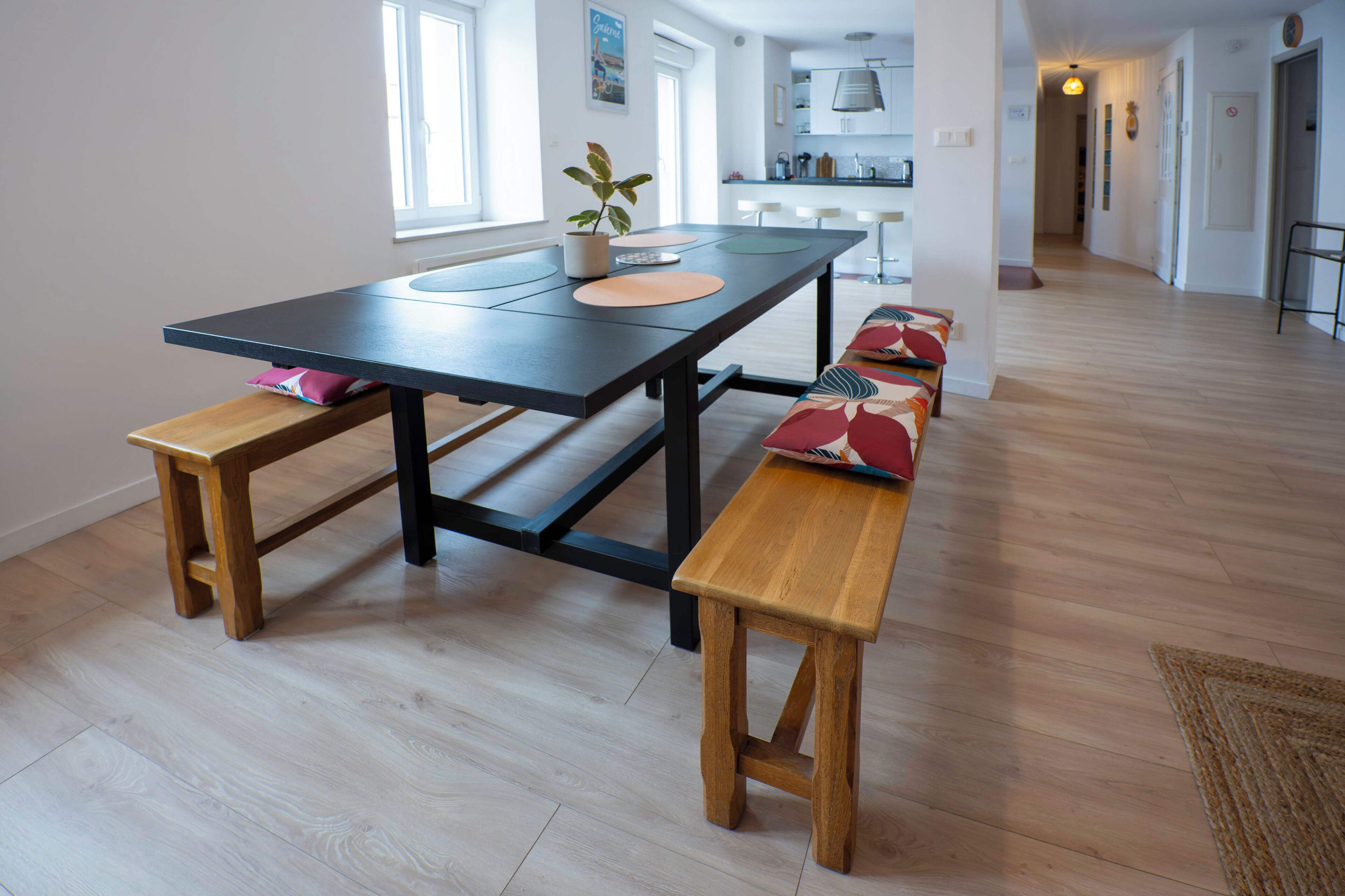 Une cuisine moderne dotée d’un grand îlot central, de bancs en bois et d’une table à manger.