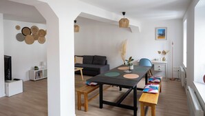 Un salon moderne comprenant une table à manger, des bancs, un canapé et un téléviseur.