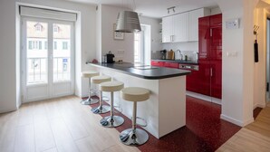 Une cuisine moderne avec un îlot central, des tabourets de bar et des meubles de couleur rouge.