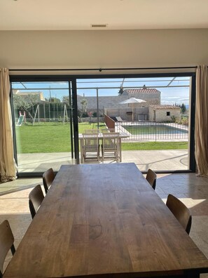 Enjoy meals at the large dining table surrounded by six chairs, with a sliding door leading to an outdoor area.