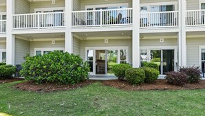 A multi-story building with balconies, a central entrance, and a well-maintained lawn. - World Tour Golf Resort Unit 103 - Golf view (Myrtle Beach)