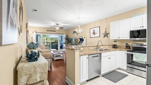 A modern kitchen with white cabinets, a granite countertop, and stainless steel appliances. - World Tour Golf Resort Unit 103 - Golf view (Myrtle Beach)