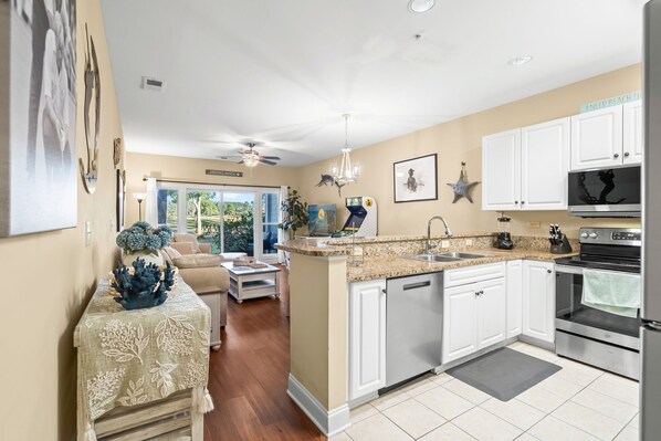 A modern kitchen with white cabinets, a granite countertop, and stainless steel appliances.