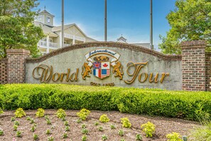 A sign for the International World Tour hotel with a brick wall and a landscaped garden in front.