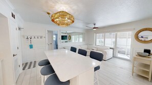 A spacious room with a dining table, chairs, a sofa, a ceiling fan, and a large window. - Crescent Arms 103S Siesta Key Florida (Sarasota)