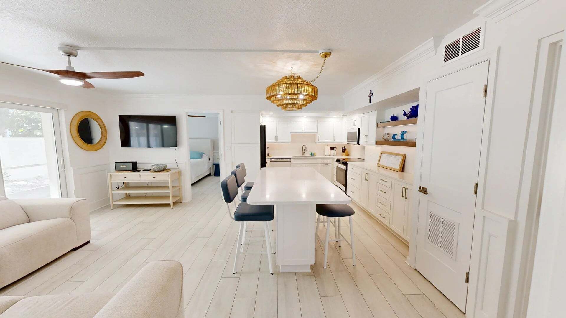 A modern kitchen with white cabinets, a central island, and a ceiling fan.
