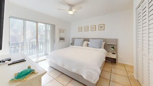 A bedroom with a bed, bedside tables, a desk, and a balcony.