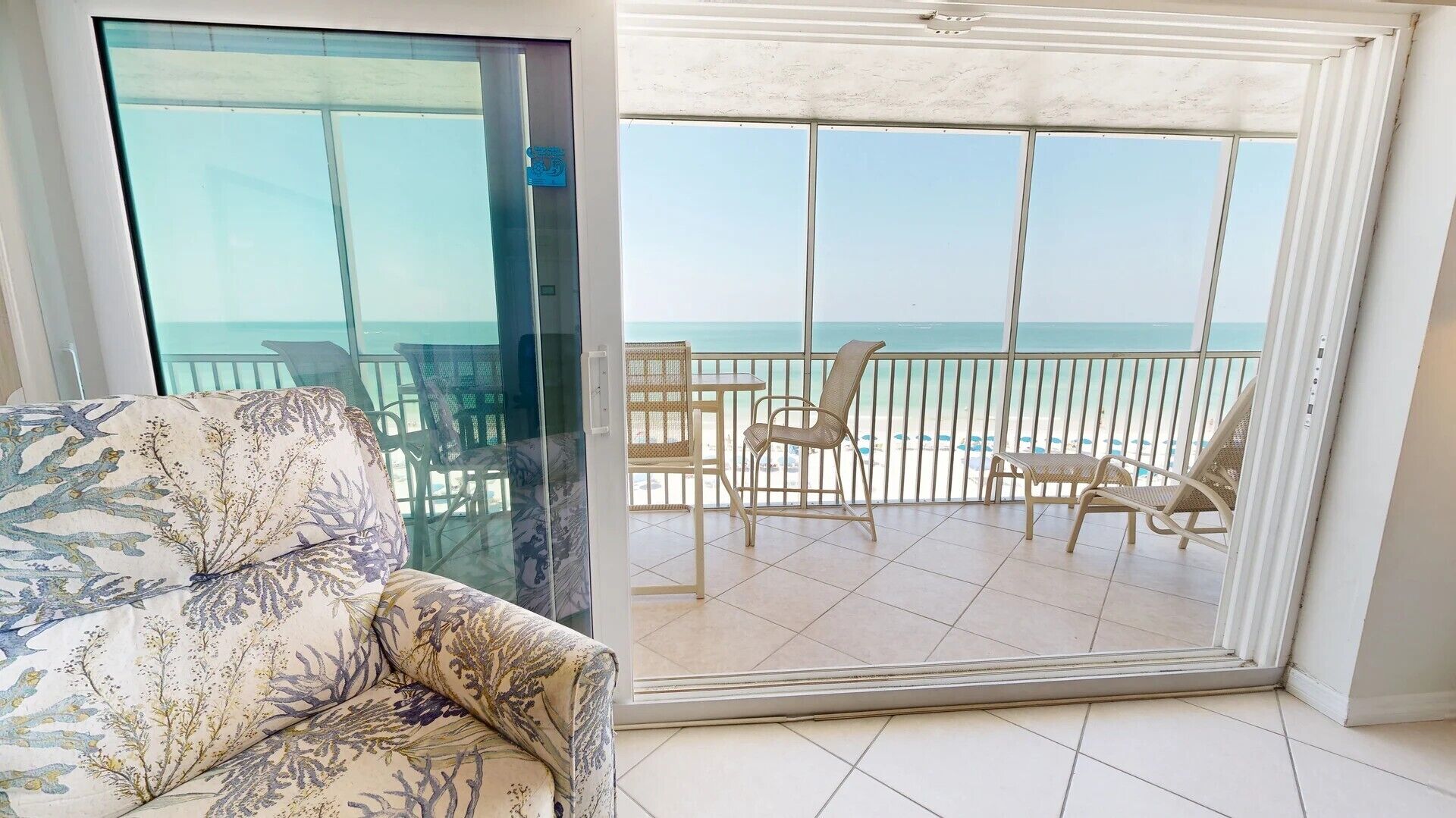 Varanda com vista para a praia, mobiliada com cadeiras de vime e uma mesa.