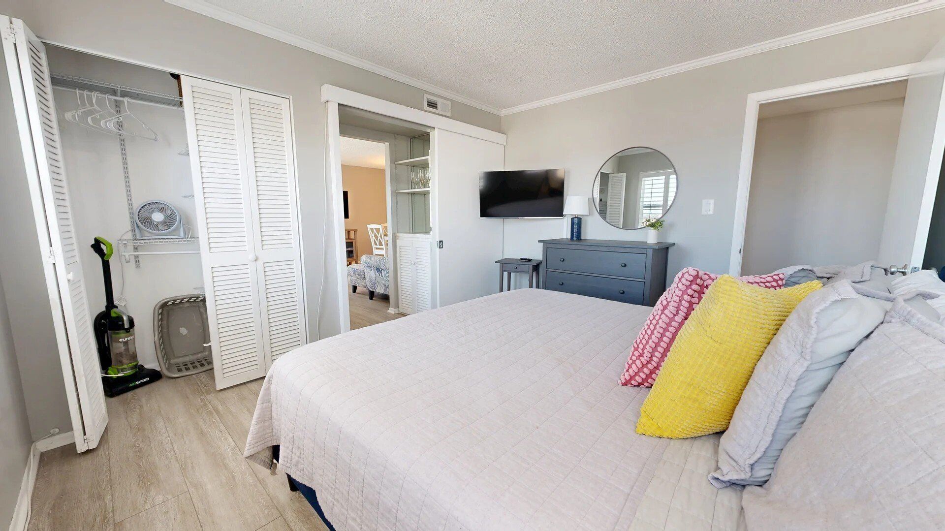 A bedroom with a bed, a TV, a dresser, and a closet.