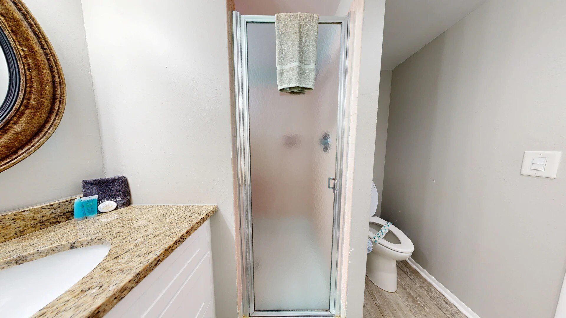 A bathroom with a shower, toilet, and a sink with toiletries.