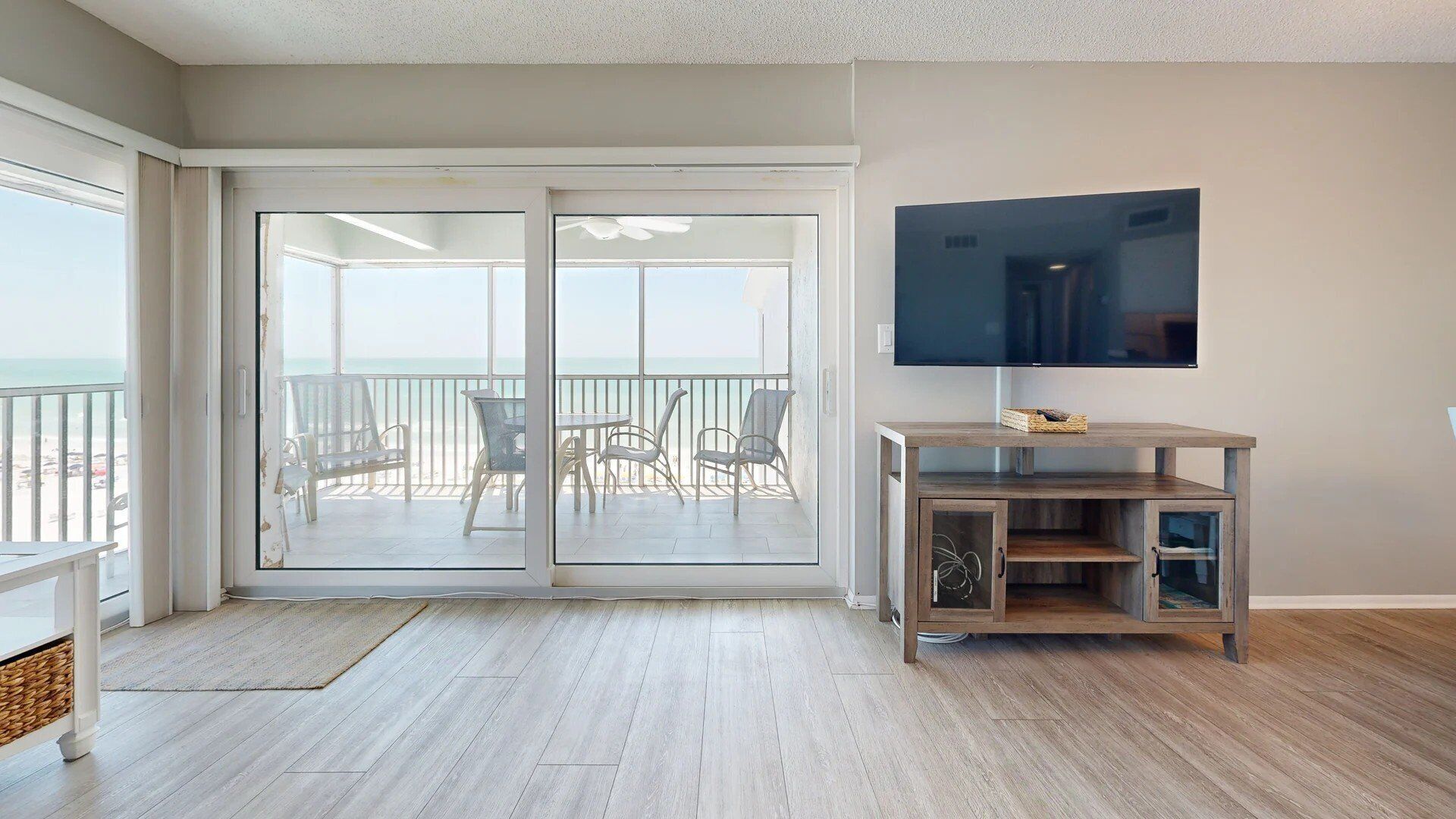 Een ruime woonkamer met een grote schuifglazen deur die leidt naar een balkon met uitzicht op de oceaan.