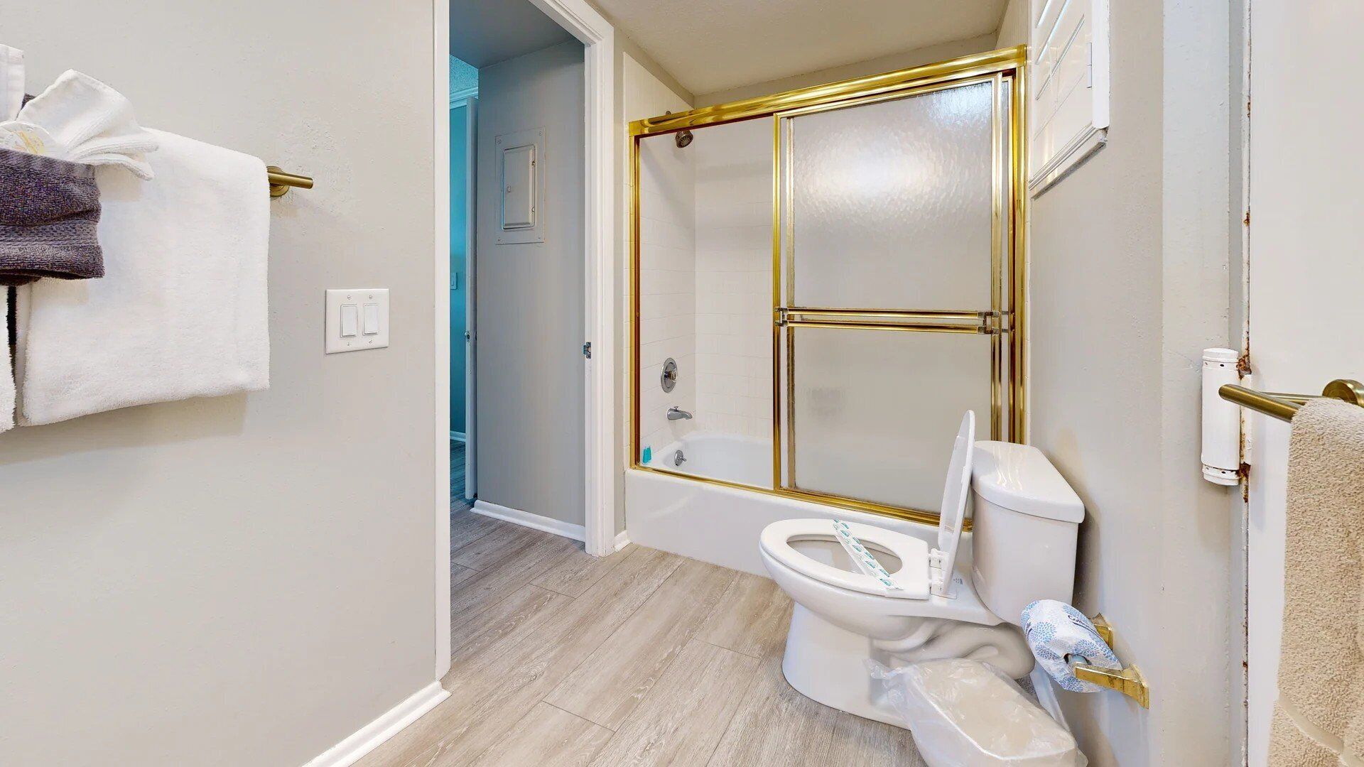 Une salle de bain avec des toilettes blanches, une douche en verre et un porte-serviettes avec des serviettes.