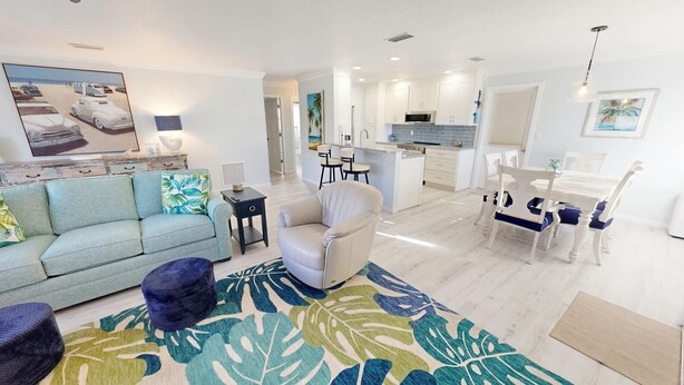 A spacious living room with a sofa, armchair, and a dining area with a table and chairs. - Crescent Arms Vacation Rentals Villa 2 Siesta Key Florida (Sarasota)