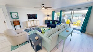 A living room with a sofa, armchair, TV, and a ceiling fan. - Crescent Arms Vacation Rentals Villa 2 Siesta Key Florida (Sarasota)