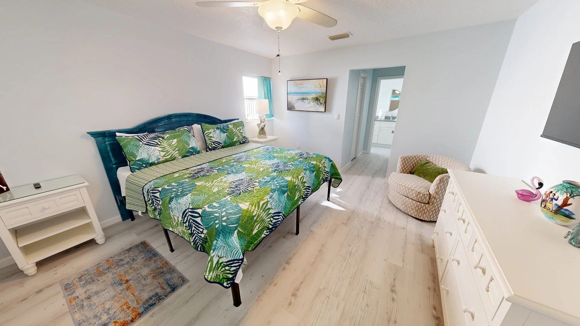 A bedroom with a bed, a nightstand, a dresser, a chair, and a ceiling fan.