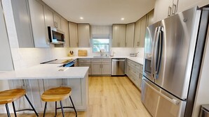 A modern kitchen with a central island, stainless steel appliances, and light wood flooring. - Crescent Arms Vacation Rentals Villa 9 Siesta Key Florida (Sarasota)