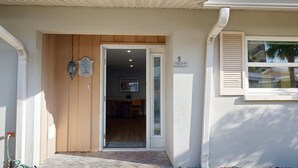 A house entrance with a wooden door, a welcome sign, and a window with blinds. - Crescent Arms Vacation Rentals Villa 9 Siesta Key Florida (Sarasota)