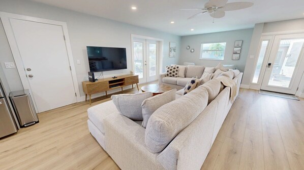 A spacious living room with a large sofa, a TV, and a wooden entertainment unit.