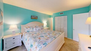 A bedroom with a bed, nightstands, a dresser, a wardrobe, and a painting on the wall. - Crescent Arms Vacation Rentals 205N Siesta Key Florida (Siesta Key)