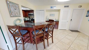 A kitchen with a dining area, featuring wooden chairs, a granite countertop, and a microwave. - Crescent Arms Vacation Rentals 205N Siesta Key Florida (Siesta Key)